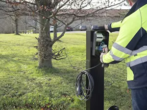 Worker installing electric vehicle charging station