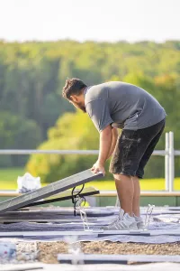 Worker installing solar panel with green landscape in the background