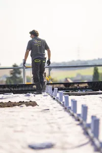 Worker looking at a solar system on a roof with a sunny view
