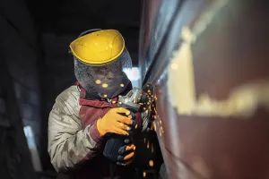 A worker uses an angle grinder with sparks flying in an industrial setting
