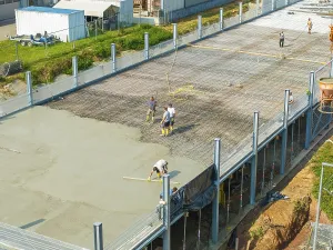 Workers on a construction site smoothing concrete surfaces and using tools