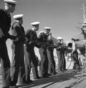 During World war II. The war ship Sverige during navy exercises at sea. The sailors are cleaning the cannon's inside pipe with a pole that on the end has something oiled that greases and cleans the cylindric pipe. Sweden june 1940