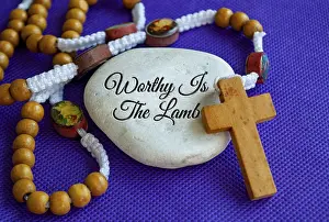 Worthy is the Lamb text engraved on white stone with Holy Rosary on purple cloth