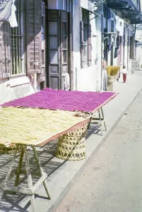 Woven bamboo mats laid out on trestle table outside traditional building