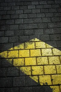 A yellow arrow marking on dark textured pavement draws attention