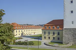 Yellow castle building with red roof in an open courtyard under a blue sky