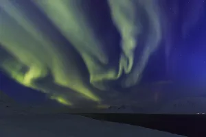Yellow and green northern lights over snowy mountains