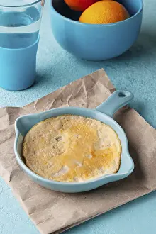 Yellow omelette in a blue frying pan, on the table