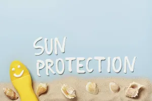 Yellow tube with happy sunscreen face with SUN PROTECTION word on blue background