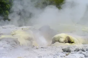 Yellowish sulphur deposit on volcanic rock formations with rising steam