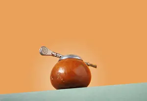 Yerba and bombilla on a green podium on an orange background