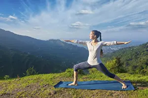 Yoga outdoors, sporty fit woman doing yoga asana Virabhadrasana 2