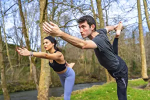 Yoga teachers performing a balancing asana by a river in the forest