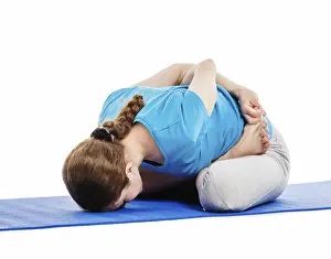 Yoga, young beautiful slender woman yoga instructor doing Psychic Union Pose (forward bend baddha padmasana)