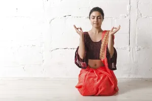 Young adult indian woman in sari meditating yoga zen like with ok sign mudra gesture