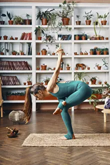 Young beautiful woman doing yoga balance asana at home