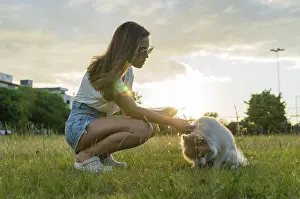 Young beautiful woman playing with German Spitz dog in the summer park