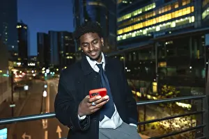 Young black businessman on an elevated walkway at night