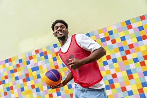 Young black man happily holding a basketball