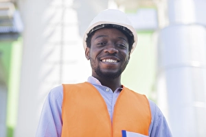 Young black man working outside as technician with helmet and safety vest