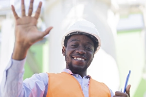 Young black man working outside as technician with helmet and safety vest