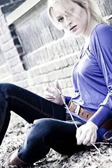 Young blond girl outside on a street posing against the wall