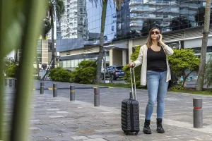 Young businesswoman walks with her suitcase on wheels on a paved street