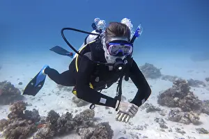 Young caucasian diver floating underwater in blue sea