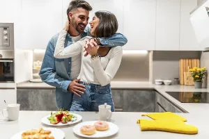 Young couple hugging and laughing in their modern kitchen