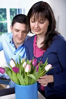 Young couple looking at tulips in a vase