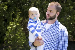 Young father holding one yeard old baby son outdoors