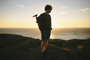 A young male photographer stands on the rocky terrain of Cape Spear Lighthouse