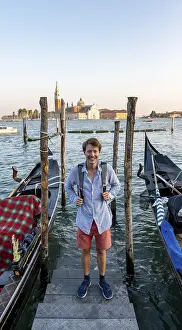 Young man at a boat dock for Venetian gondolas in St