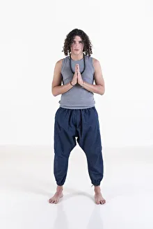 Young man clasping hands while looking at camera over white background