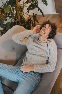 Young man with curly hair relaxes on a modern gray couch