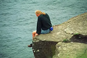 Young man sitting on a cliff edge