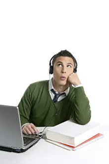 Young man student, computer, hearing music with headphones over white