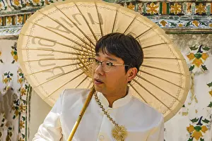 Young man wearing a parasol in traditional clothing presents himself for the photographers