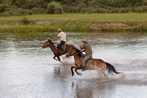 Young Mongolian horseman rides at full gallop on the river