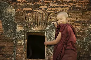 Young novice monk standing outside Buddhist temple