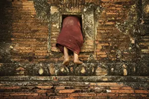 Young novice monks climbing into Buddhist temple from window