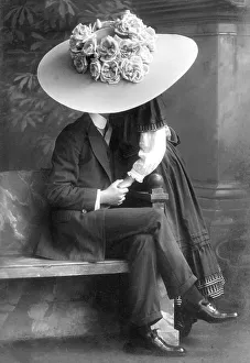 Young pair kissing under a giant hat