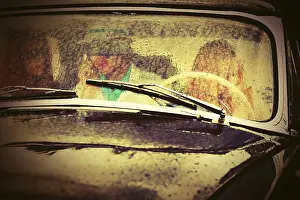 Young people driving vintage car in the rain