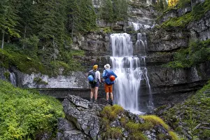 Young pretty hiker standing on rocks in front of Cascata di Mezzo waterfall