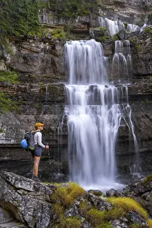 Young pretty hiker standing on rocks in front of Cascata di Mezzo waterfall