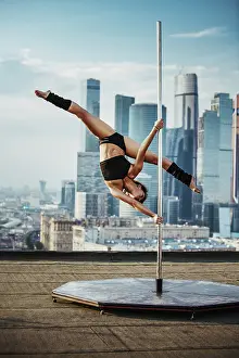 Framed Print : Young slim woman in black lingerie pole dancing on modern city background