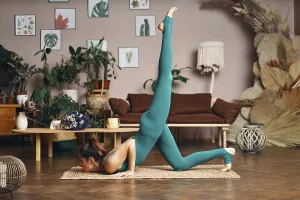 Young sporty woman practicing yoga at home doing asana Trianga Dandasana