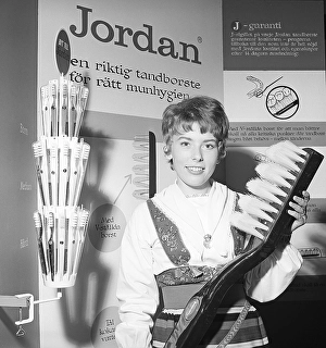 A young woman from the company Jordan is standing in their booth at an exhibition