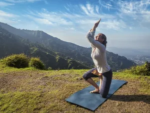 Young woman doing Ashtanga Vinyasa yoga advanced difficult asana Vatayanasana (Horse pose)