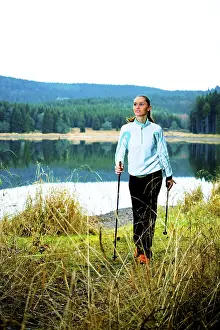 Young woman doing nordic walking beside a lake